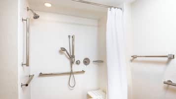 Ein modernes Badezimmer mit weiß gefliesten Wänden, einer Dusche mit Duschbrause sowie einer Haltegriffe.