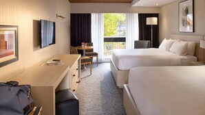 Una habitación de hotel con dos camas, un escritorio, una silla, una lámpara y una ventana con cortinas.