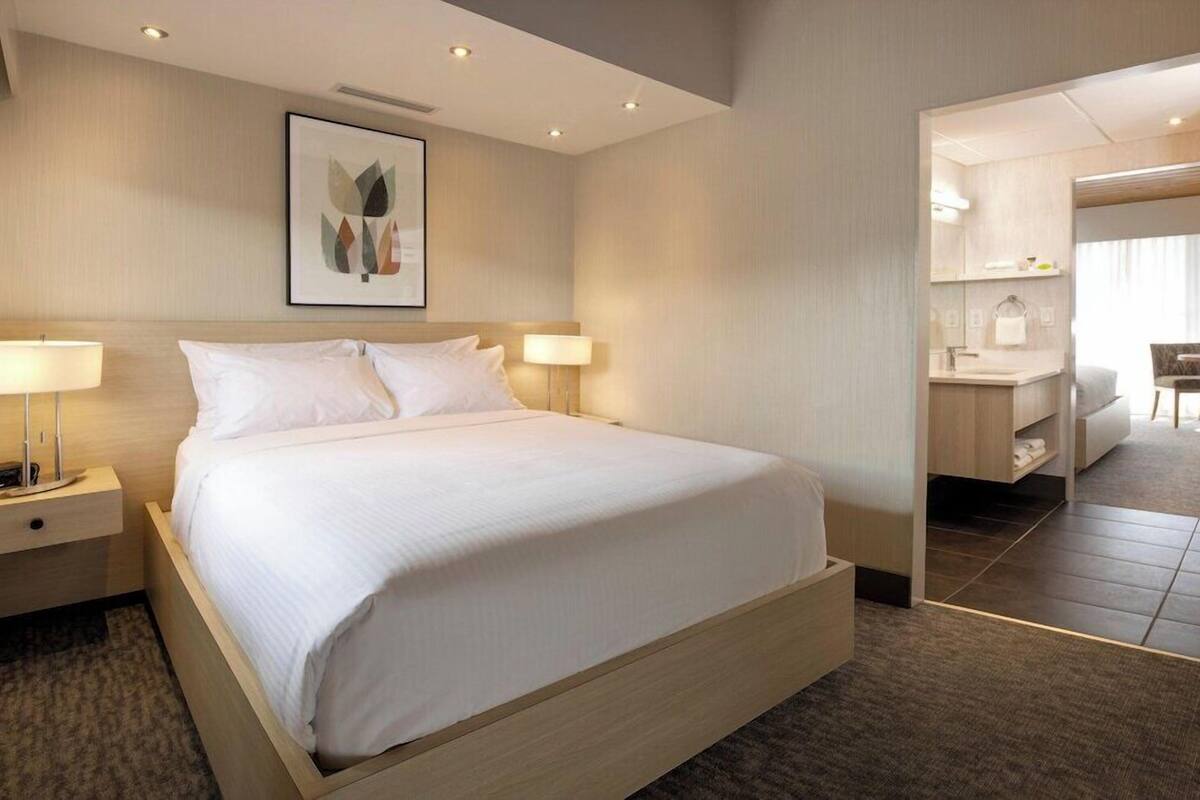 A hotel room with a bed, bedside tables, a desk, and a mirror.