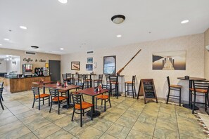 Een restaurant met meerdere tafels en stoelen, een koffiebar en een krijtbordmenu.