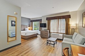 Een hotelkamer met een bed, een bank, een televisie, een dressoir en een spiegel.