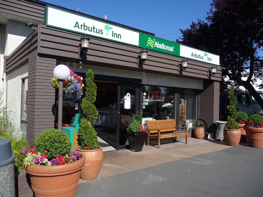 A National Arbutus Inn with a clear entrance, outdoor seating, and potted plants.