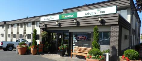 An Arbutus Inn with a National logo, outdoor seating, and potted plants.