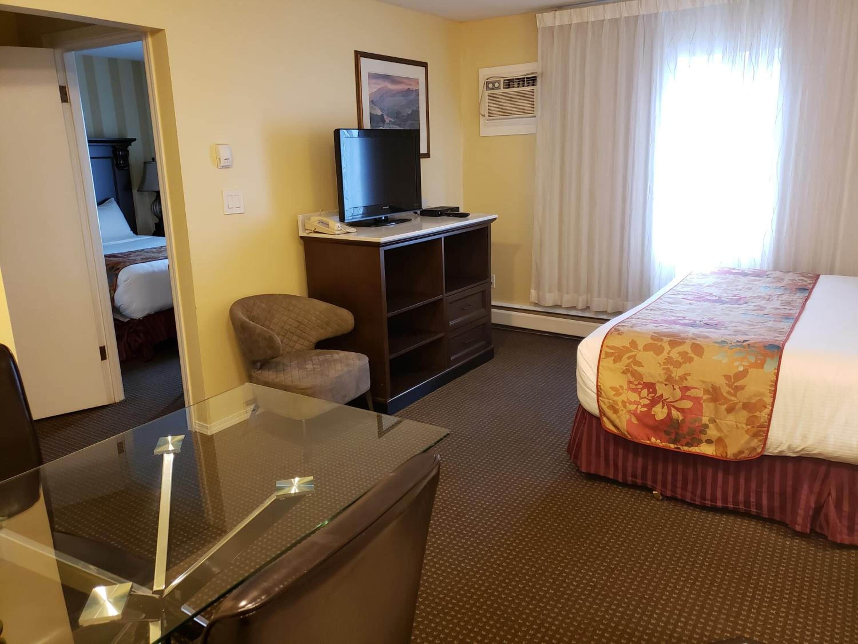 Une chambre d’hôtel équipée d’un lit, d’un bureau, d’une chaise, d’une télévision et d’une fenêtre avec des rideaux.