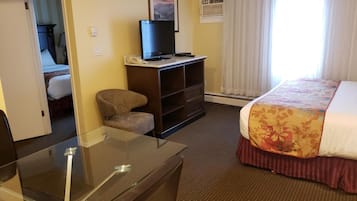 A hotel room with a bed, a desk, a chair, a television, and a window with curtains.