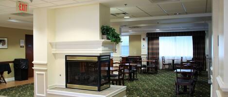 A hotel lobby with a fireplace, dining area, and an exit sign.
