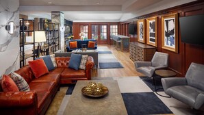 A spacious living area with leather sofas, a coffee table, and a TV mounted on the wall. - The Inn at Henderson's Wharf, an Ascend Collection Hotel (Baltimore)