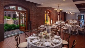 A dining area with round tables set for a meal, featuring white tablecloths, chairs, and floral centerpieces. - The Inn at Henderson's Wharf, an Ascend Collection Hotel (Baltimore)