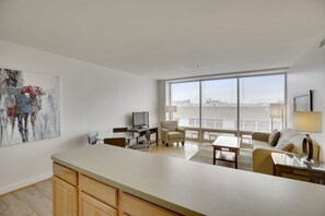 Amplia sala de estar con un gran ventanal, un comedor y una cocina con una isla central.