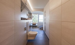 Un baño estrecho con inodoro, lavabo y ventana con vistas al exterior.