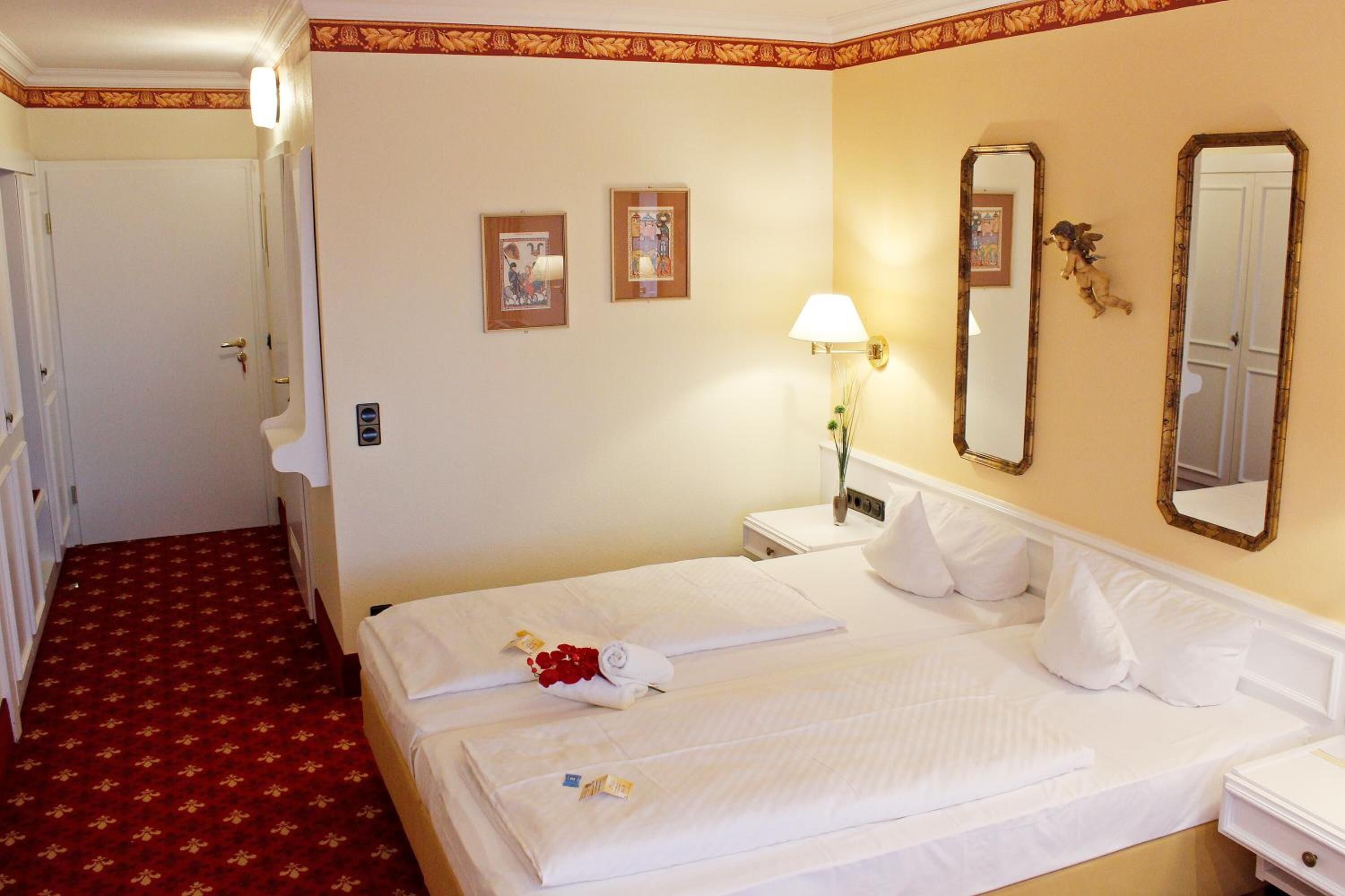 Une chambre d’hôtel avec un grand lit, une table de chevet, un miroir et deux tableaux encadrés au mur.