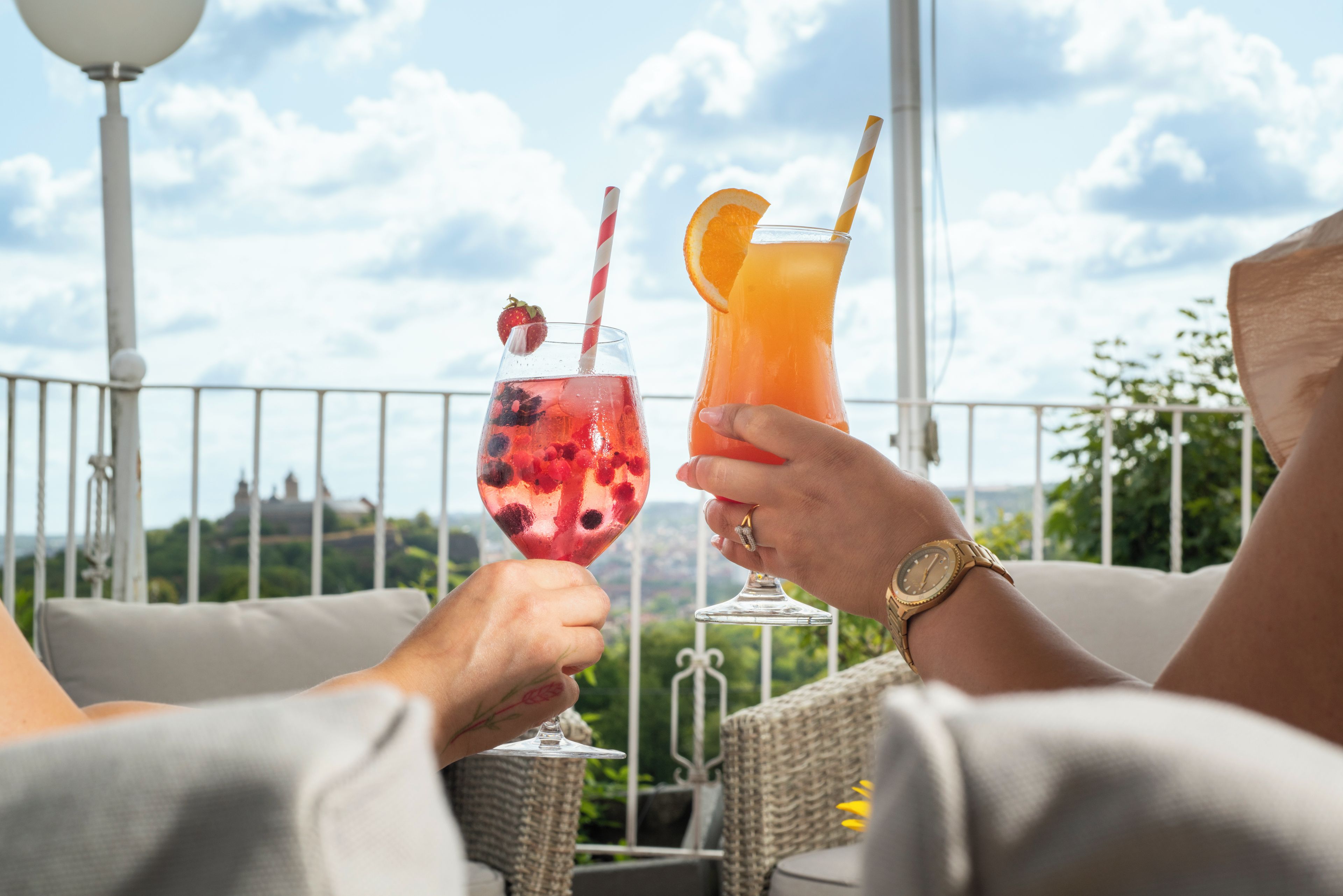 Dos personas sosteniendo bebidas con una vista panorámica al fondo.