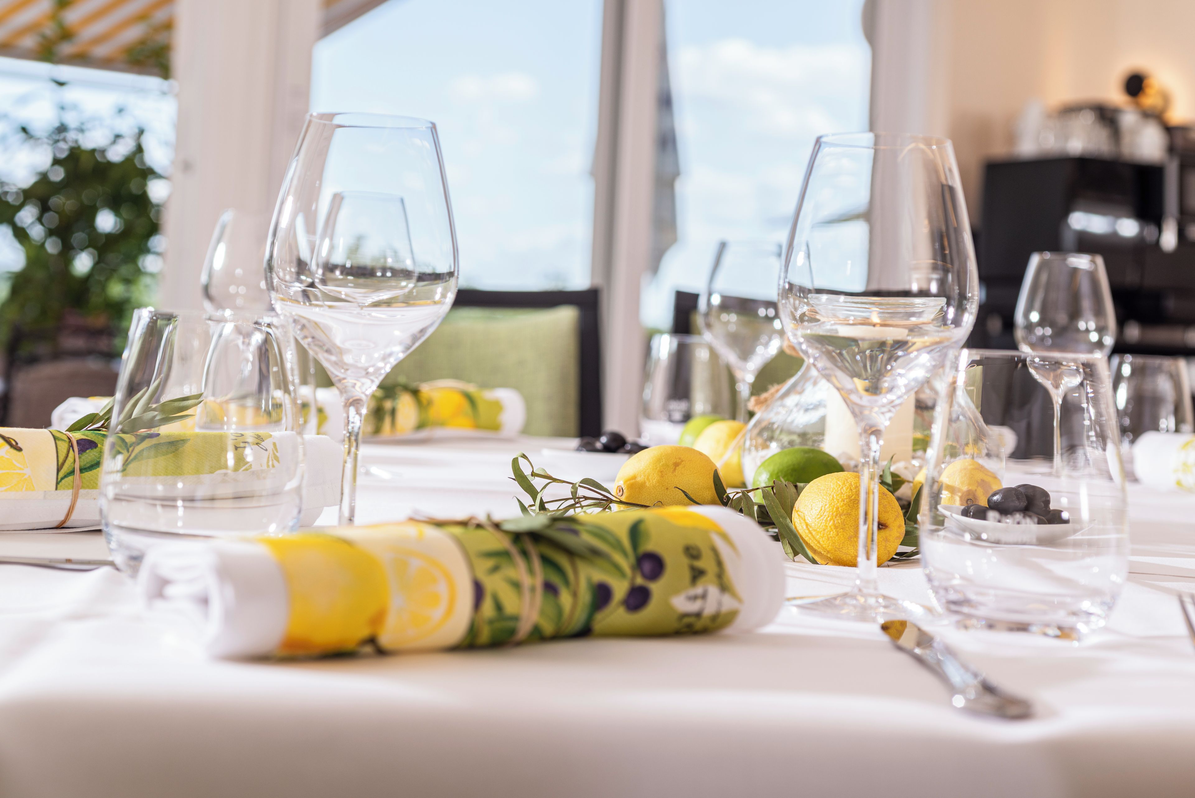 Una mesa dispuesta con copas de vino, limones y una servilleta enrollada.