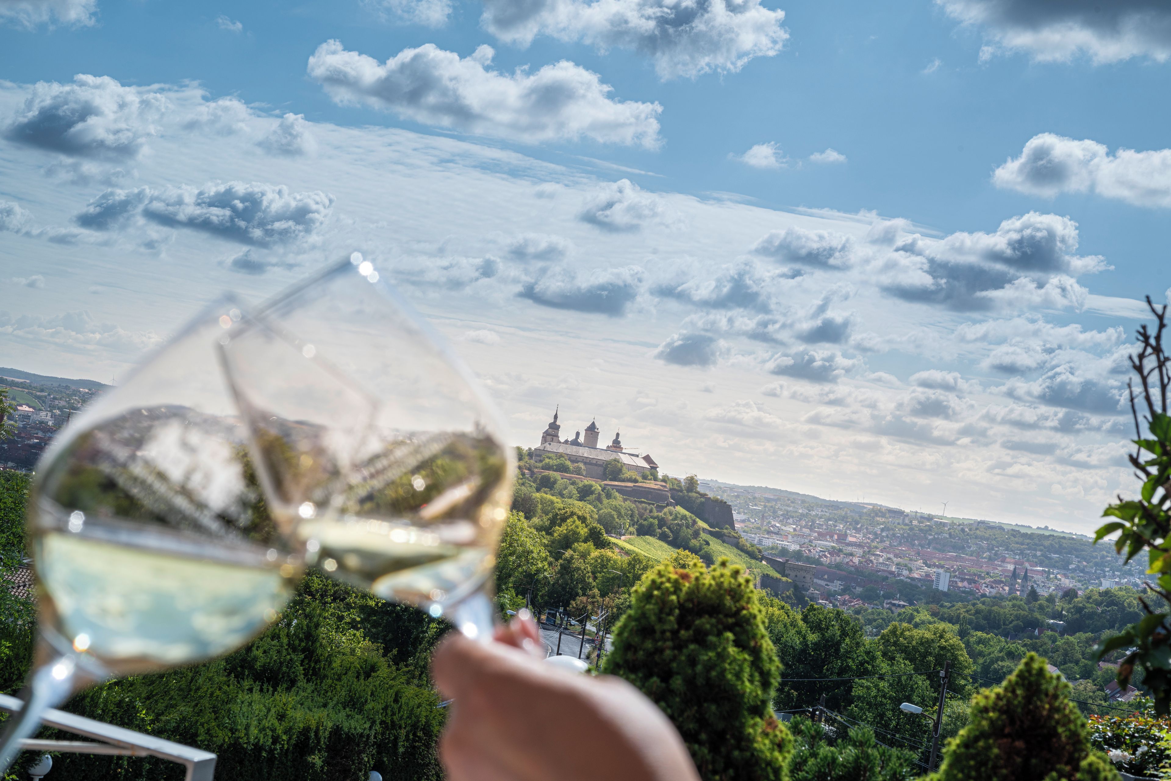 A wine glass held up with a view of a cityscape and a prominent building in the distance.