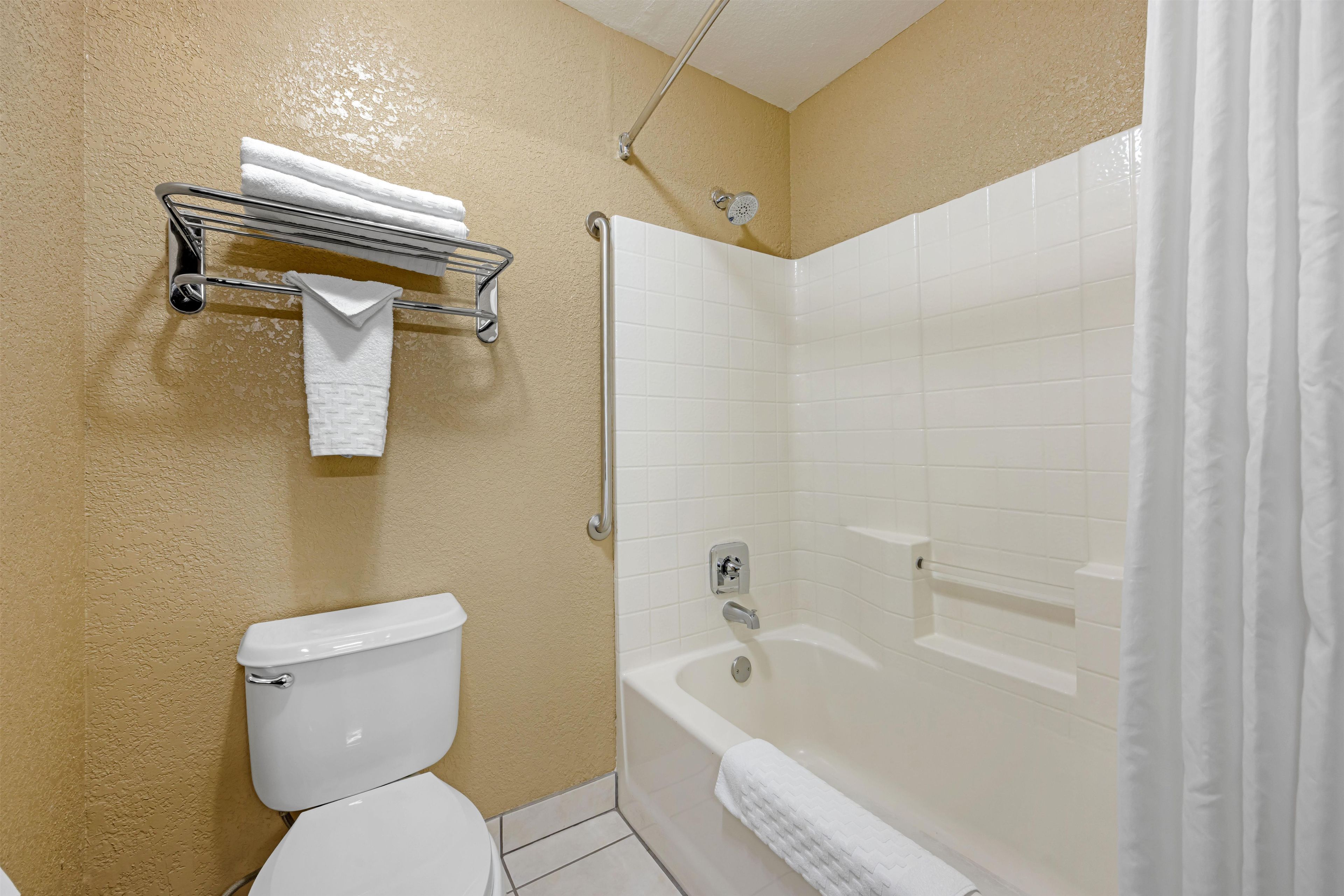 A bathroom with a toilet, a shower with a glass door, and a towel rack with a towel.