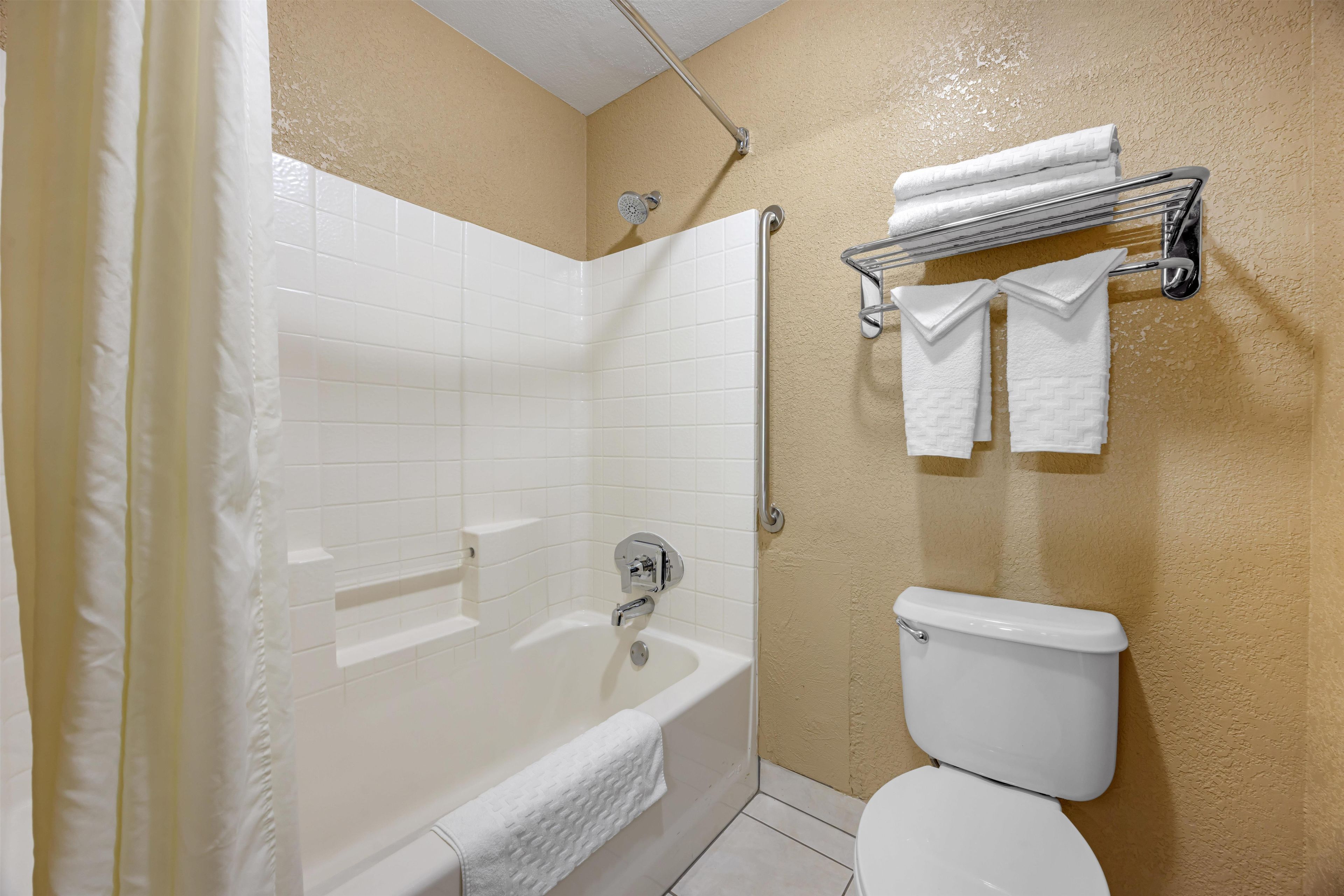 A bathroom with a bathtub, toilet, and towel rack.