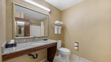 A bathroom with a granite countertop, a mirror, a toilet, and a towel rack.