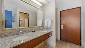 A bathroom with a double sink vanity, a large mirror, and a wooden door.