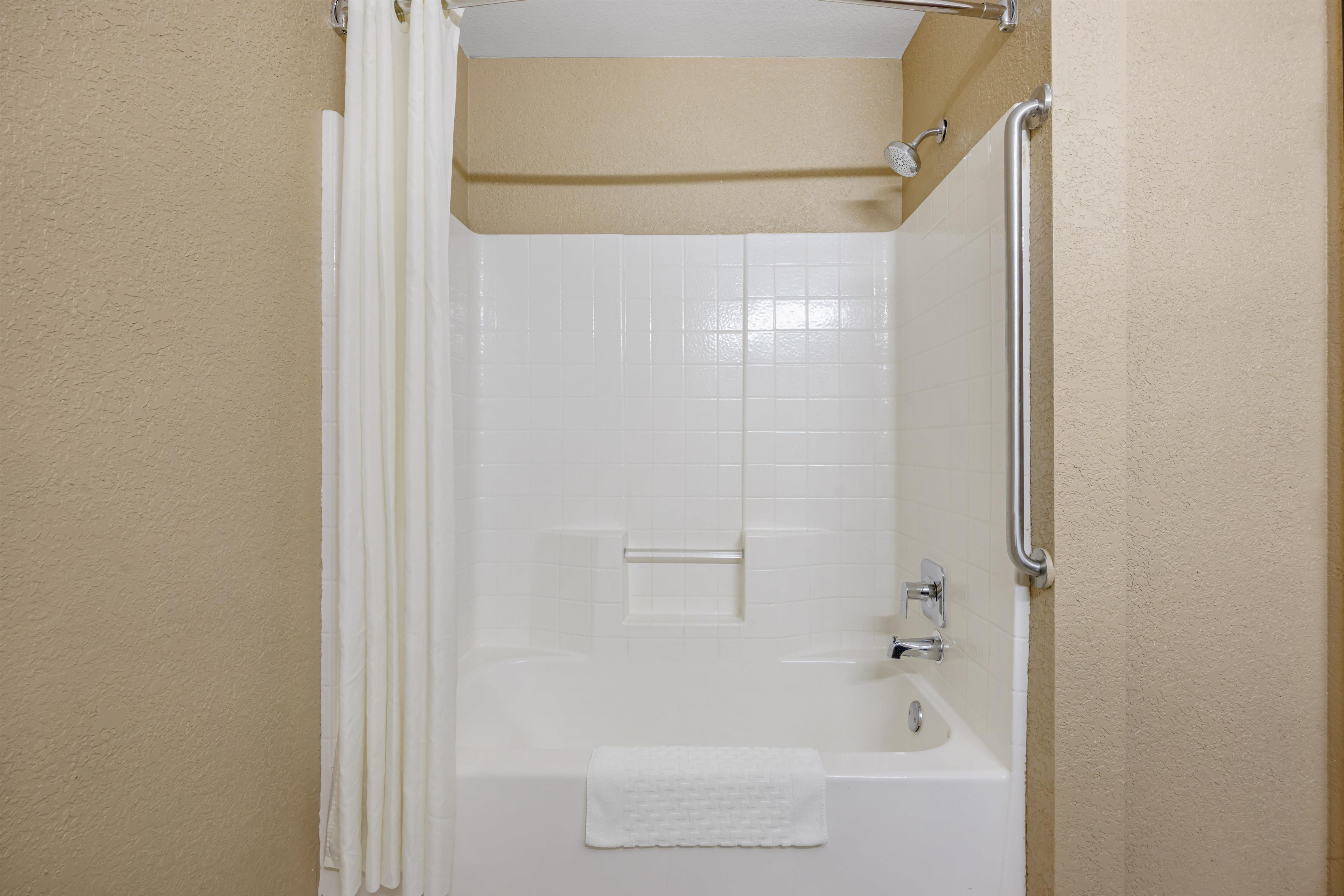 A bathroom with a bathtub, a shower, and a towel rack.