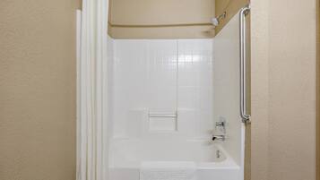 A bathroom with a bathtub, a shower, and a towel rack.