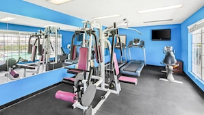 A gym with exercise equipment, a treadmill, and a TV on the wall. - Baymont by Wyndham Forest City (Forest City)