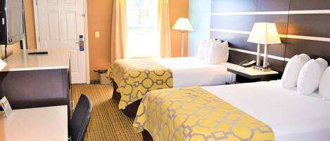 A hotel room with two beds, a desk, a chair, a TV, and a window with curtains.
