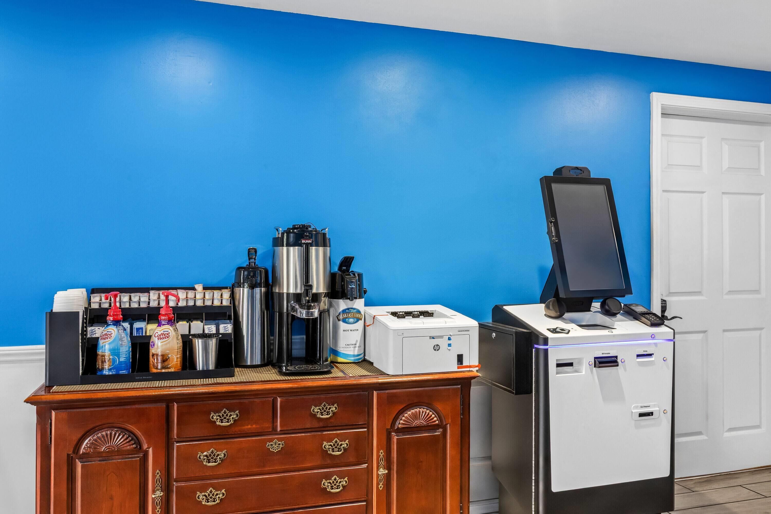 Ein Kaffee-Bereich mit Kaffeemaschine, Espressomaschine und Kaffeeautomaten, sowie ein Drucker auf einer Theke.