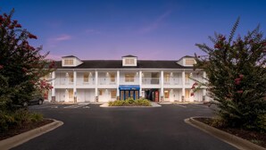 A two-story motel with a central entrance, a blue sign, and a parking lot. - Baymont by Wyndham Forest City (Forest City)