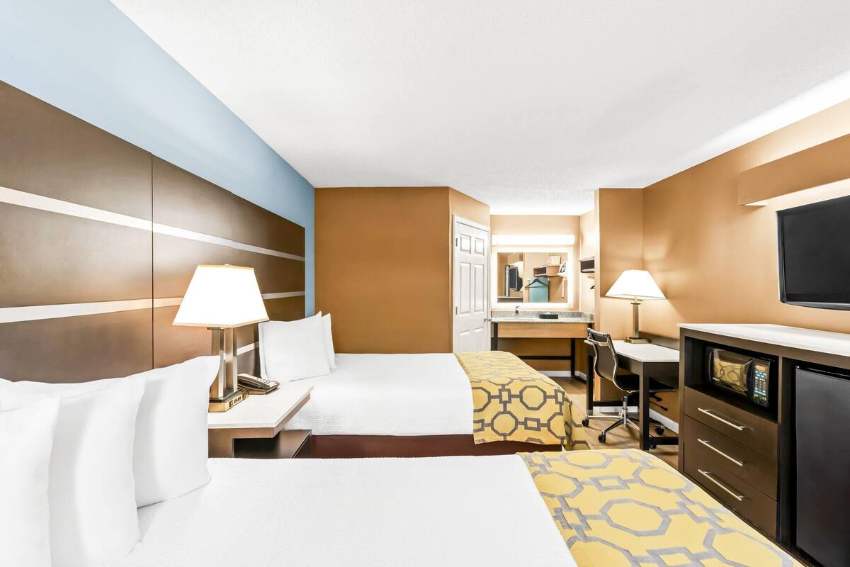 A hotel room with two beds, a desk, a TV, and a minibar.