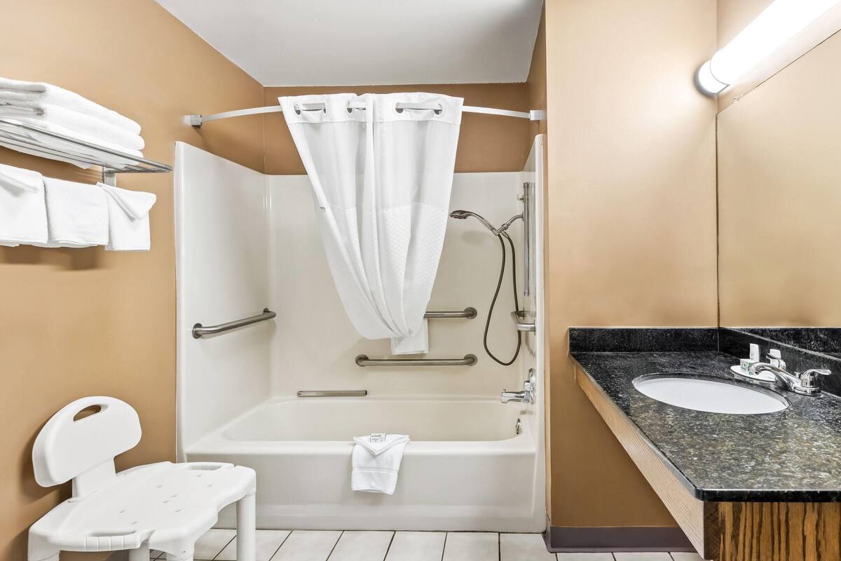 A modern bathroom with a bathtub, a shower, a sink, and a toilet.