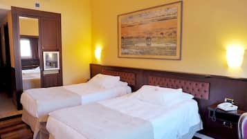 Quarto de hotel com duas camas, cabeceira de madeira, um quadro na parede e mesa de cabeceira com telefone.