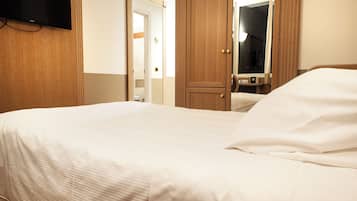 Une chambre d’hôtel avec un lit, un téléviseur fixé au mur et une armoire en bois.