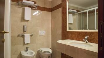 Une salle de bain équipée d’un lavabo, d’un bidet, de toilettes et d’un porte-serviettes.