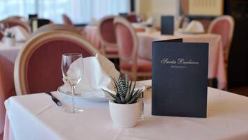 Une table à manger dressée avec un verre à vin, une serviette, une petite plante en pot et un menu.