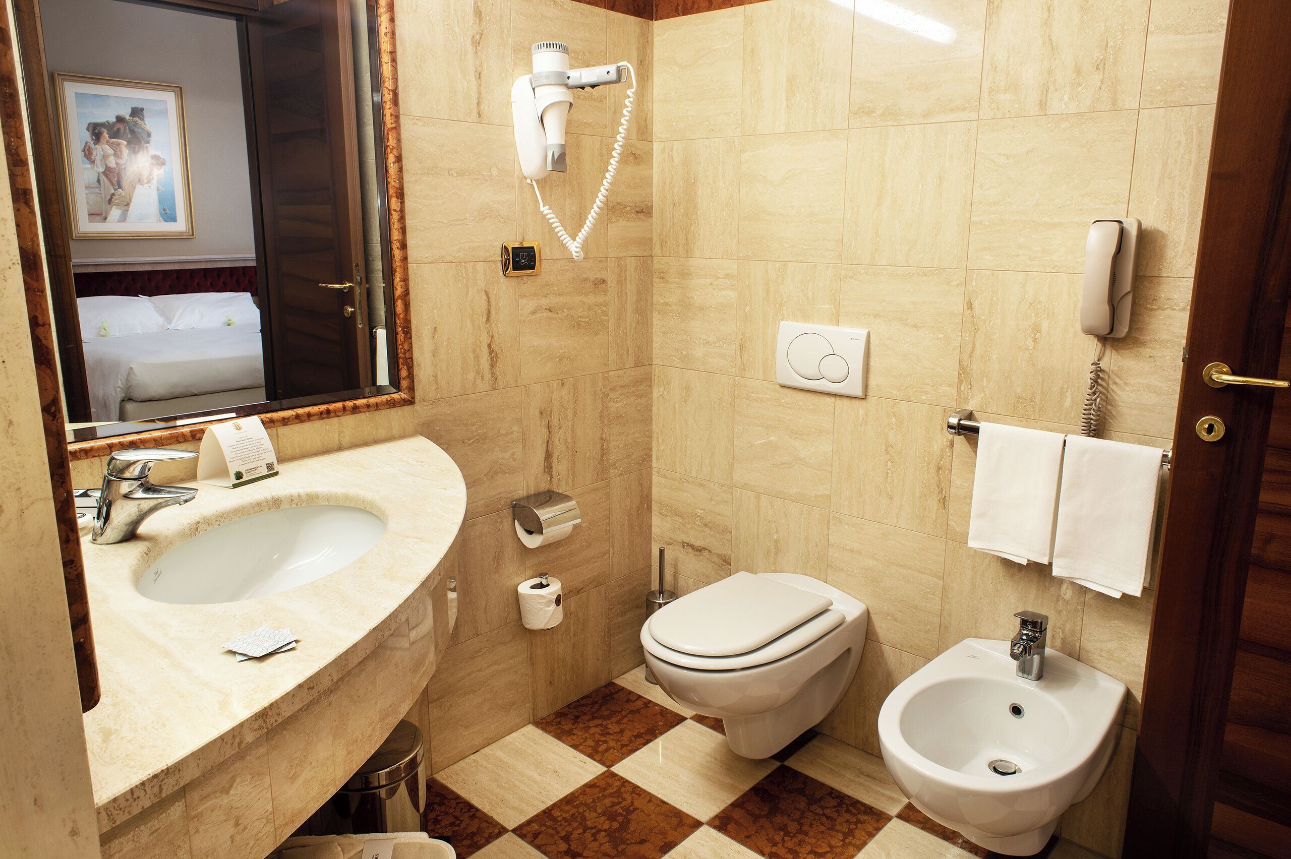 A bathroom with a sink, toilet, bidet, and a mirror.