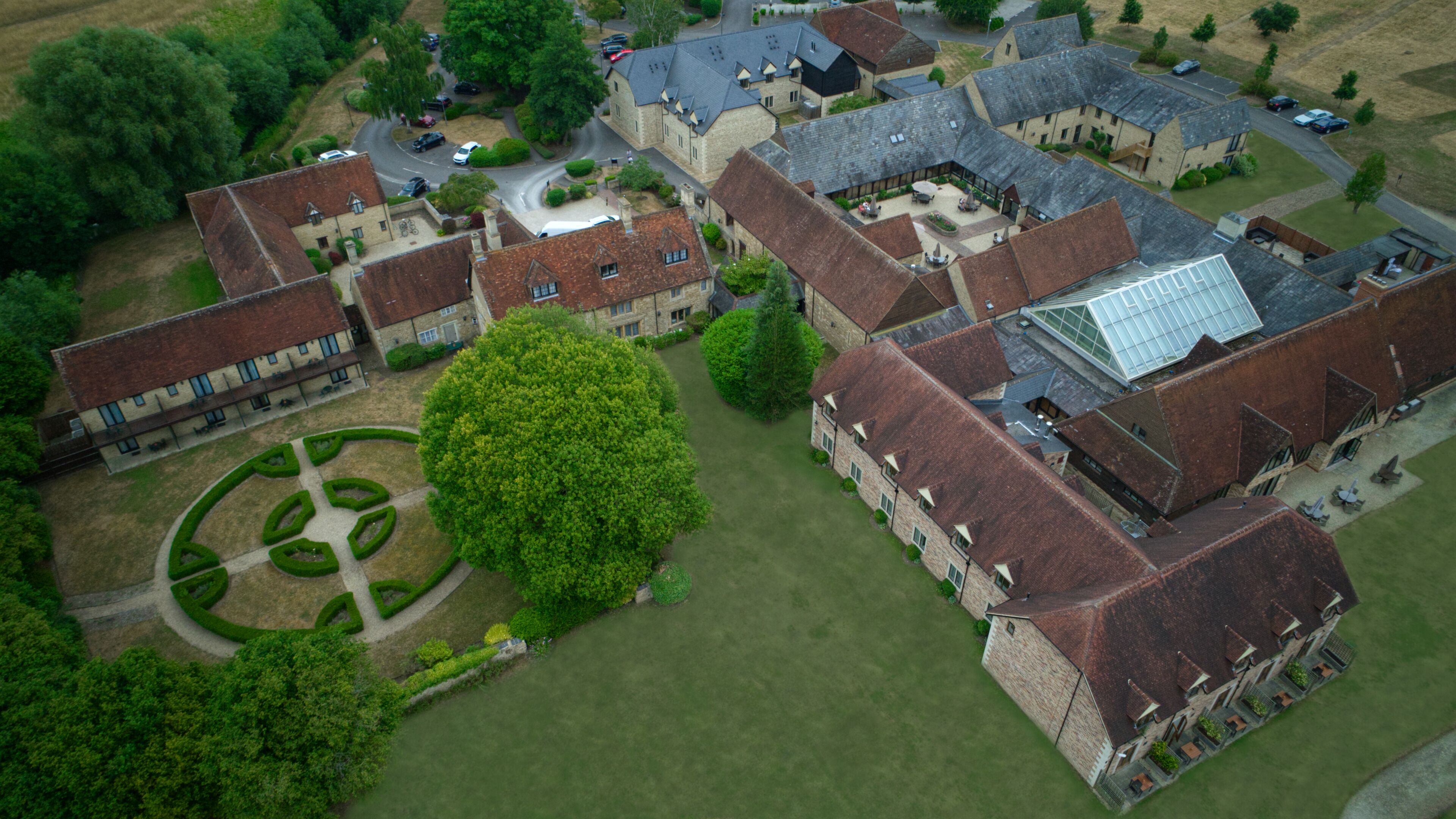 An aerial view of a large estate with multiple buildings, including a central courtyard with a circular garden, surrounded by residential and possibly commercial structures.
