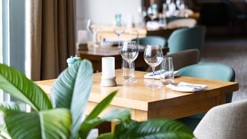 Una mesa de comedor preparada con copas de vino, una vela y un salero y pimentero.