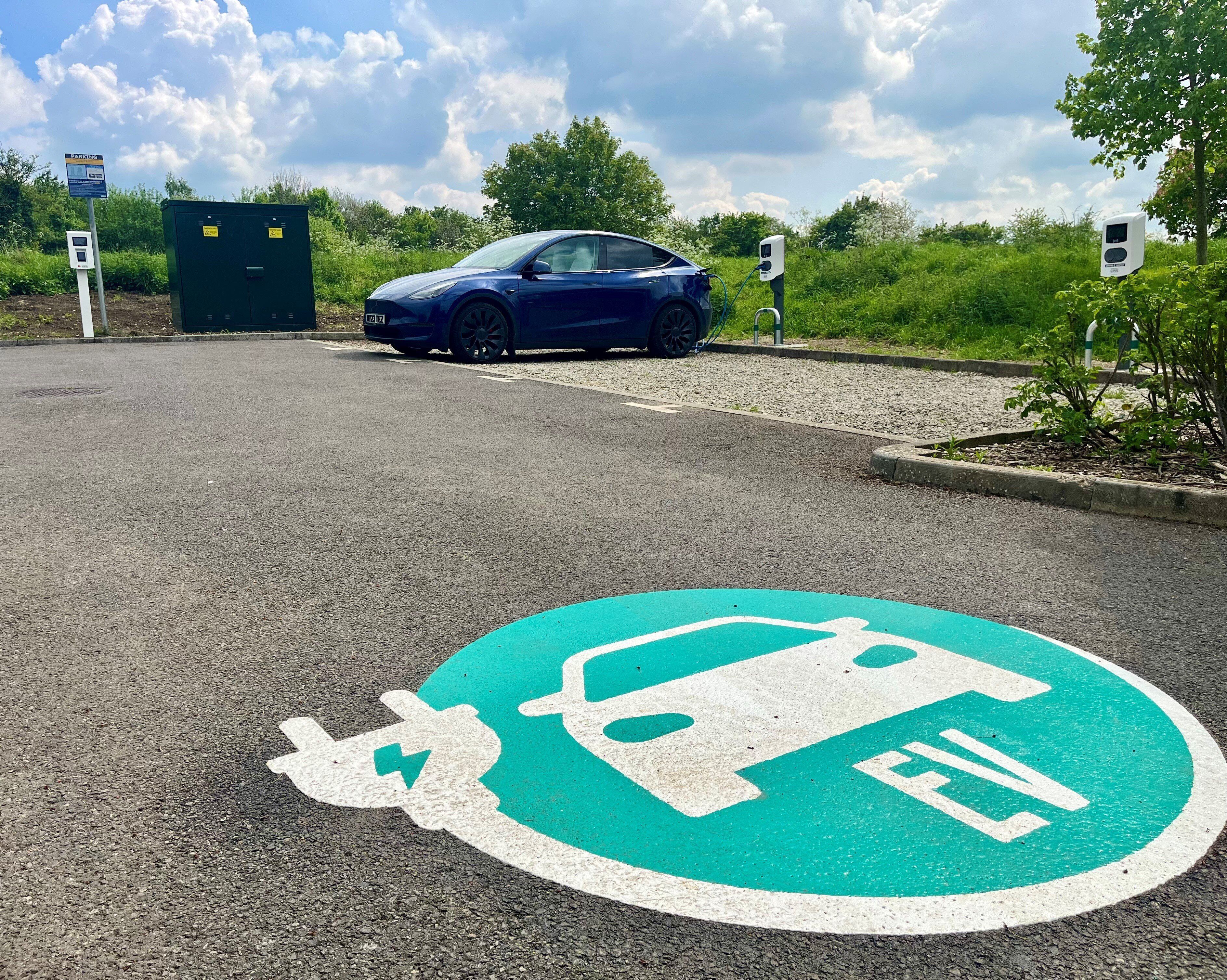 Un área de estacionamiento con estaciones de carga para vehículos eléctricos y un espacio reservado para vehículos eléctricos.