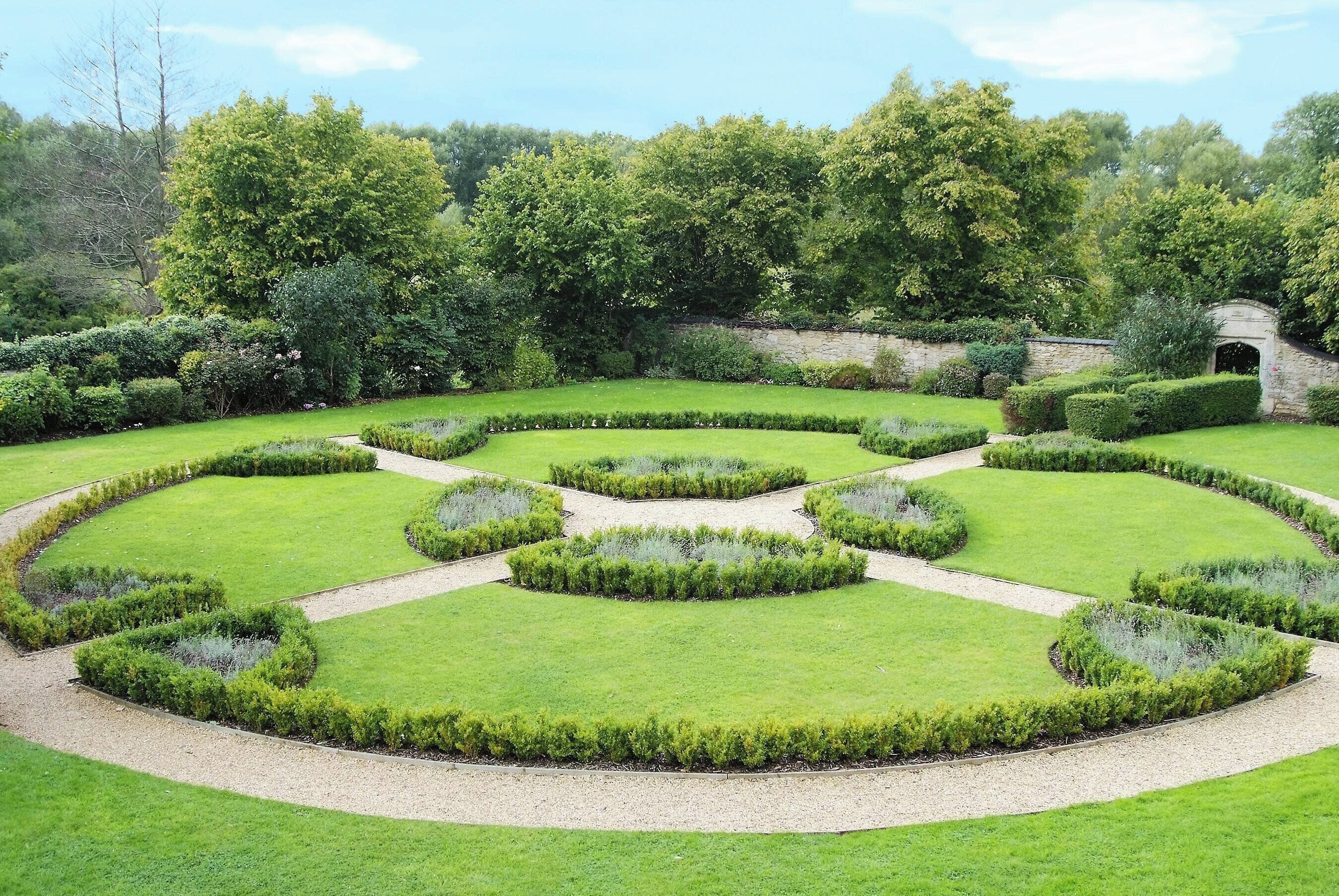 Un jardín formal con setos geométricos y una zona central de grava.