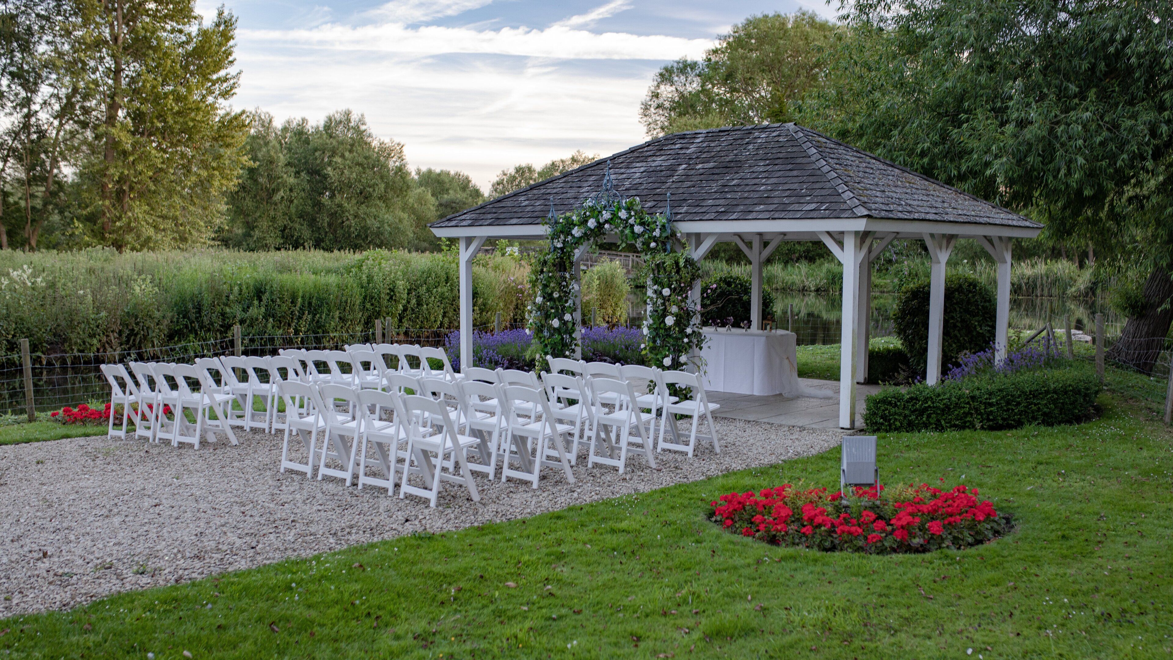 A gazebo with white chairs arranged for an event.