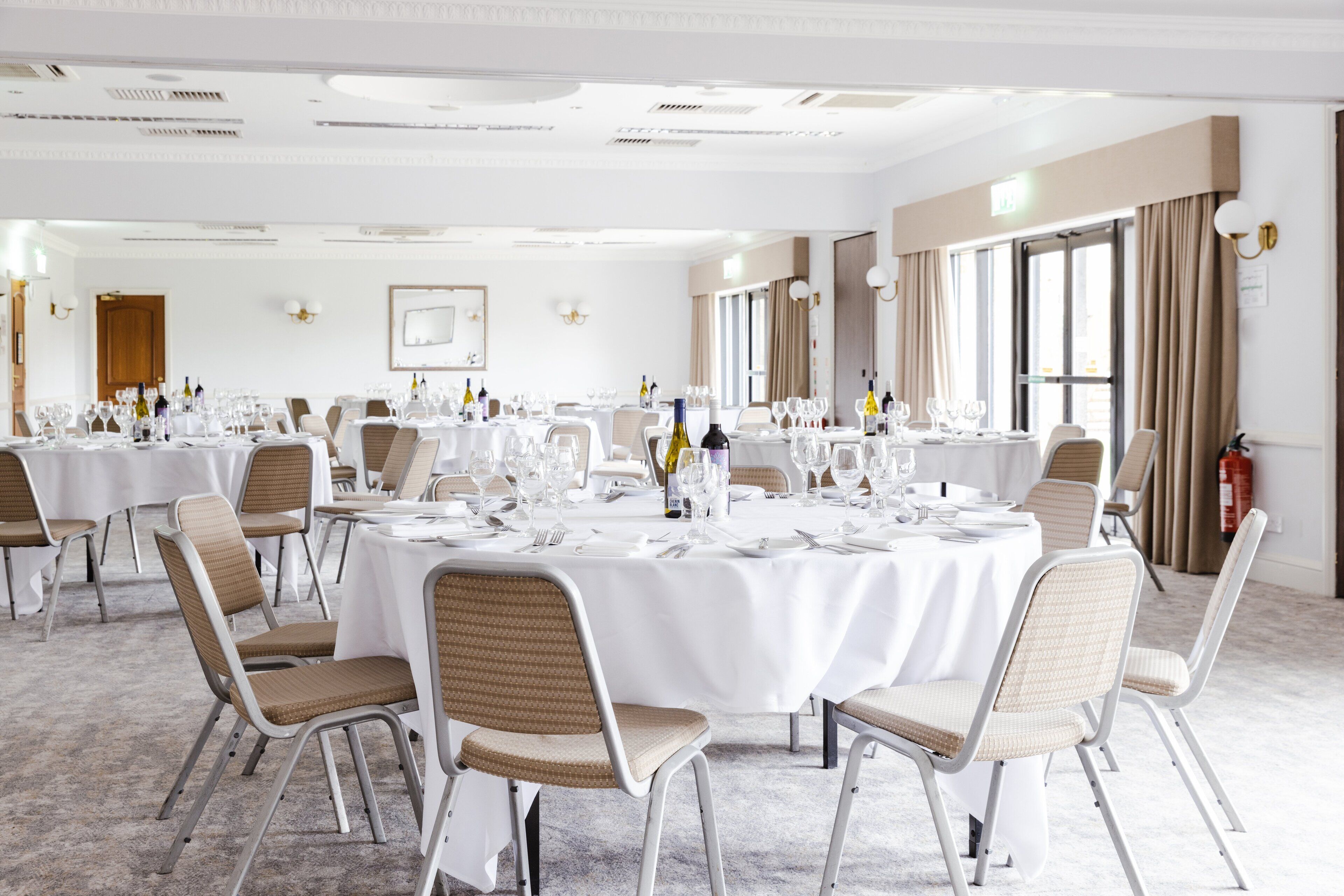 A spacious banquet hall with round tables set for dining, equipped with chairs and table settings.