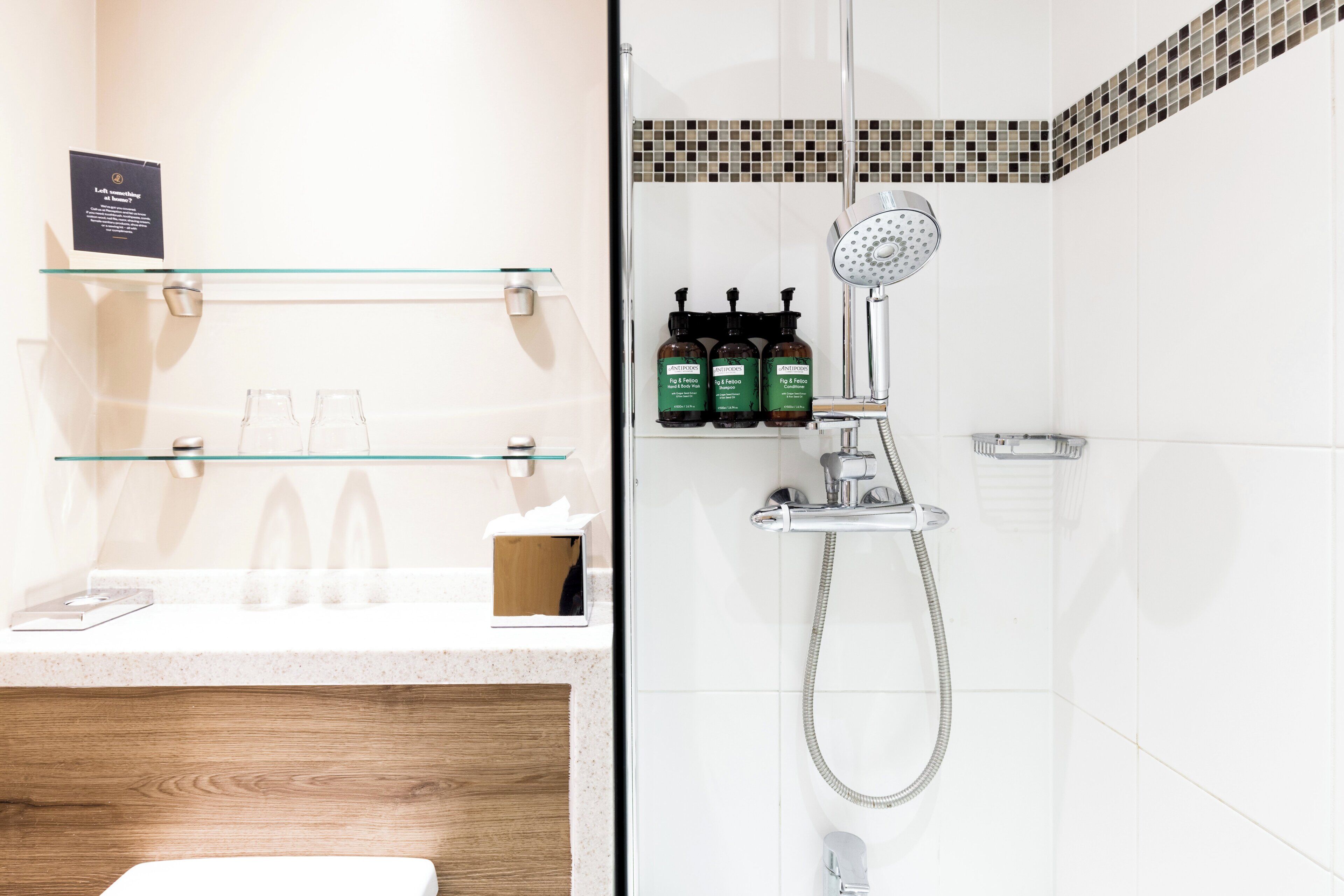 Une salle de bain moderne avec une douche à parois de verre, un meuble-lavabo en bois et une étagère contenant des articles de toilette.