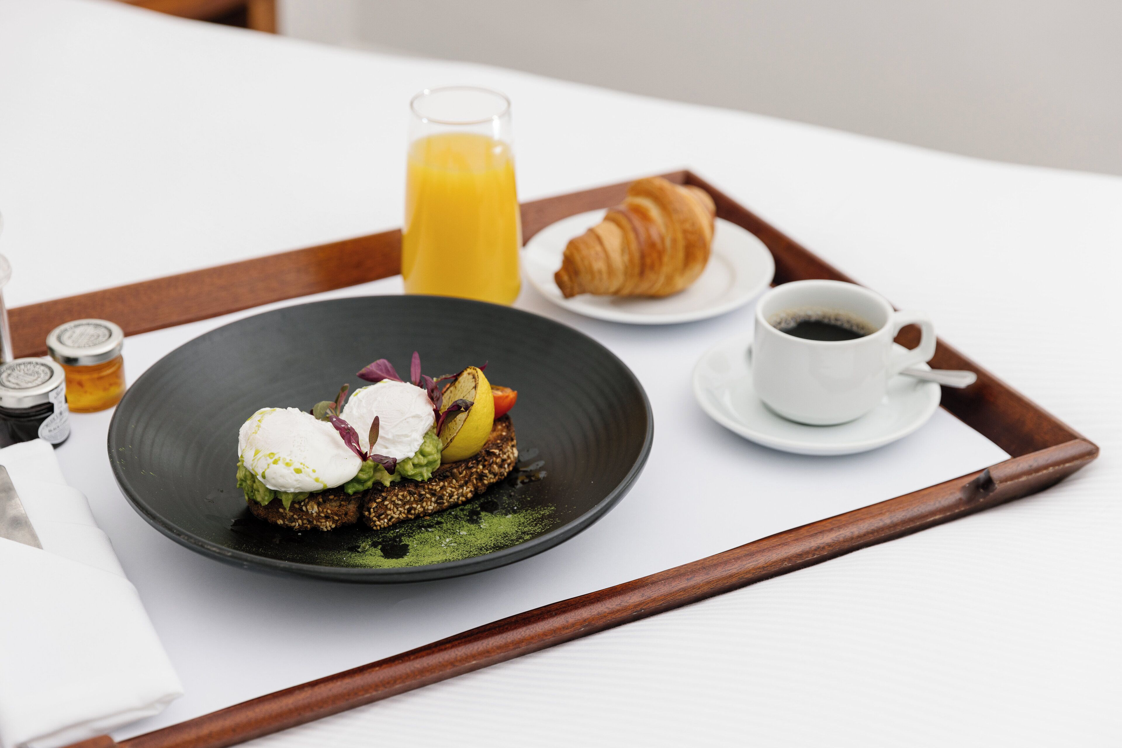 A breakfast tray with a croissant, coffee, and a plate of food.