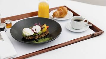 A breakfast tray with a croissant, coffee, and a plate of food.
