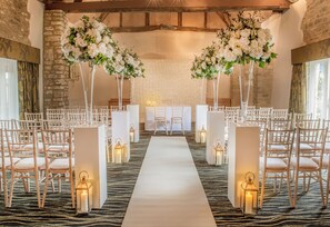 A wedding ceremony aisle with white chairs and floral arrangements. - voco Oxford Thames by IHG (Oxford)