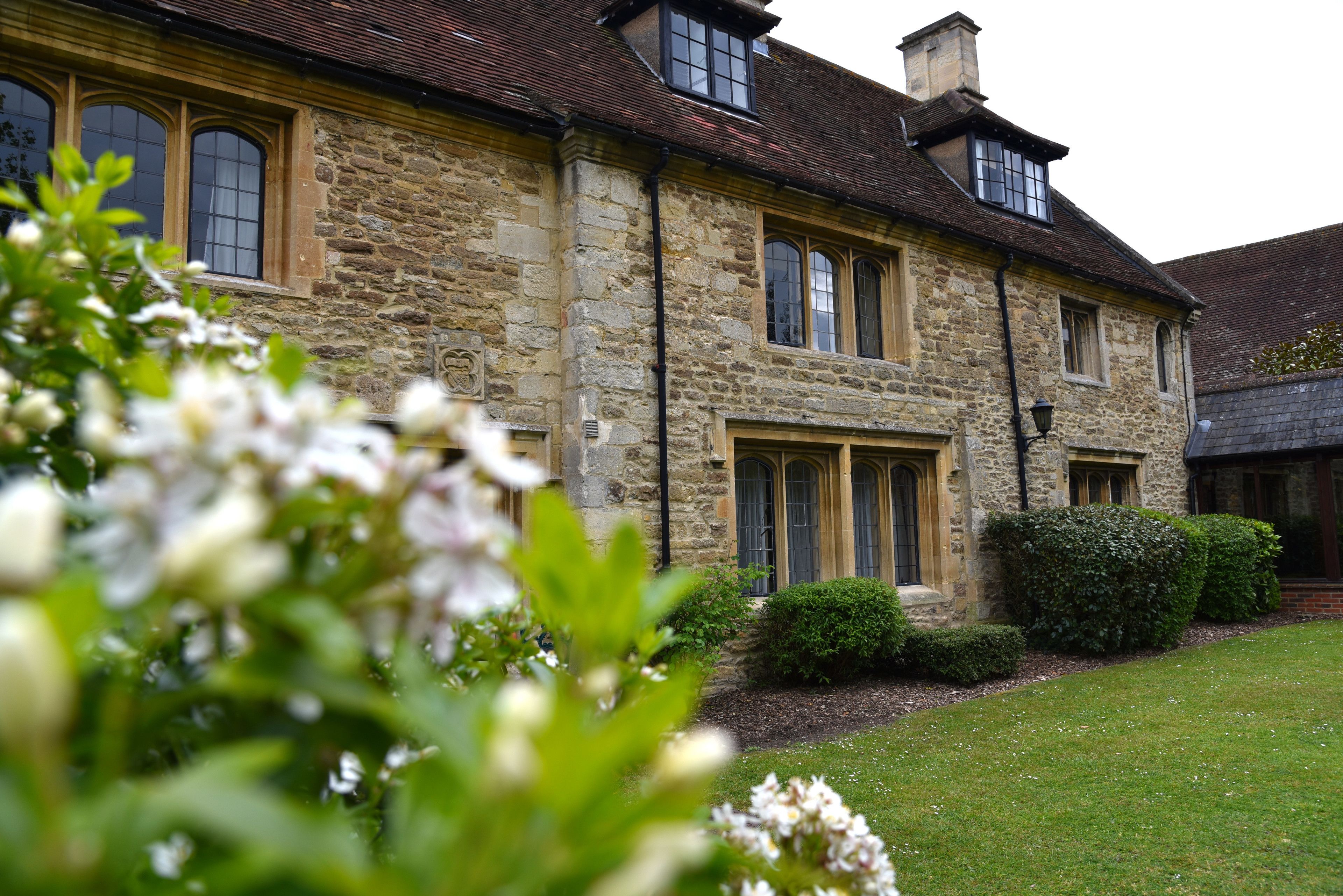 A stone building with arched windows and a well-maintained lawn.