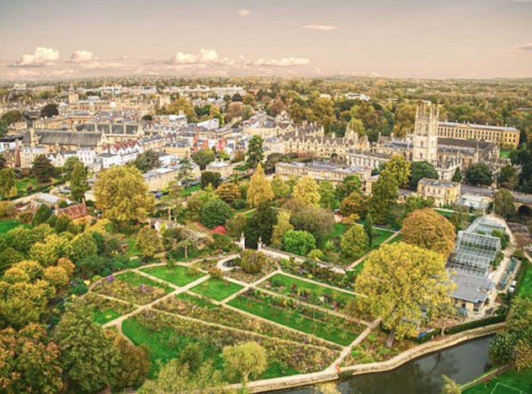 An aerial view of a university campus with historic buildings, green spaces, and a river.
