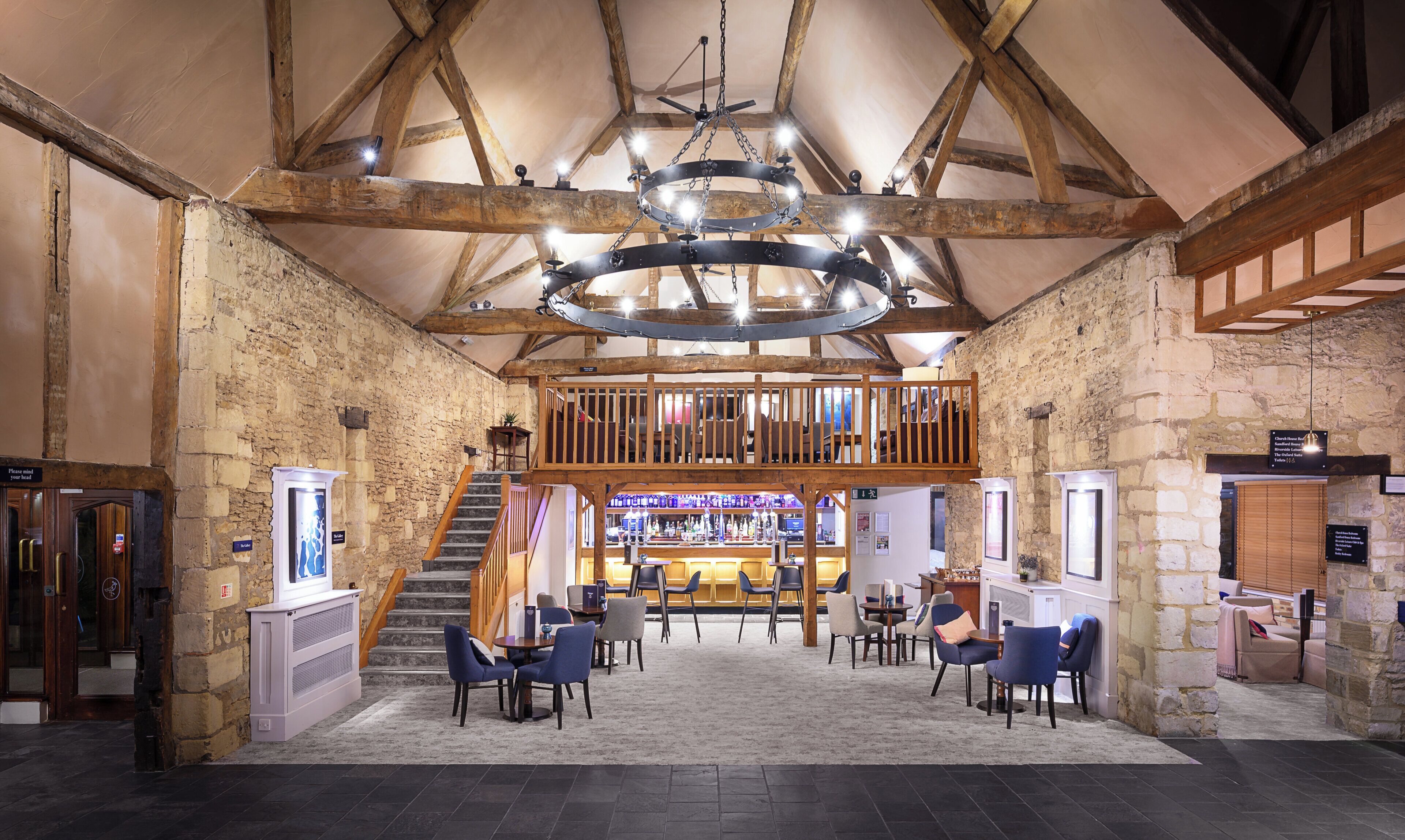 A spacious lobby with a high ceiling, stone walls, and a wooden balcony.