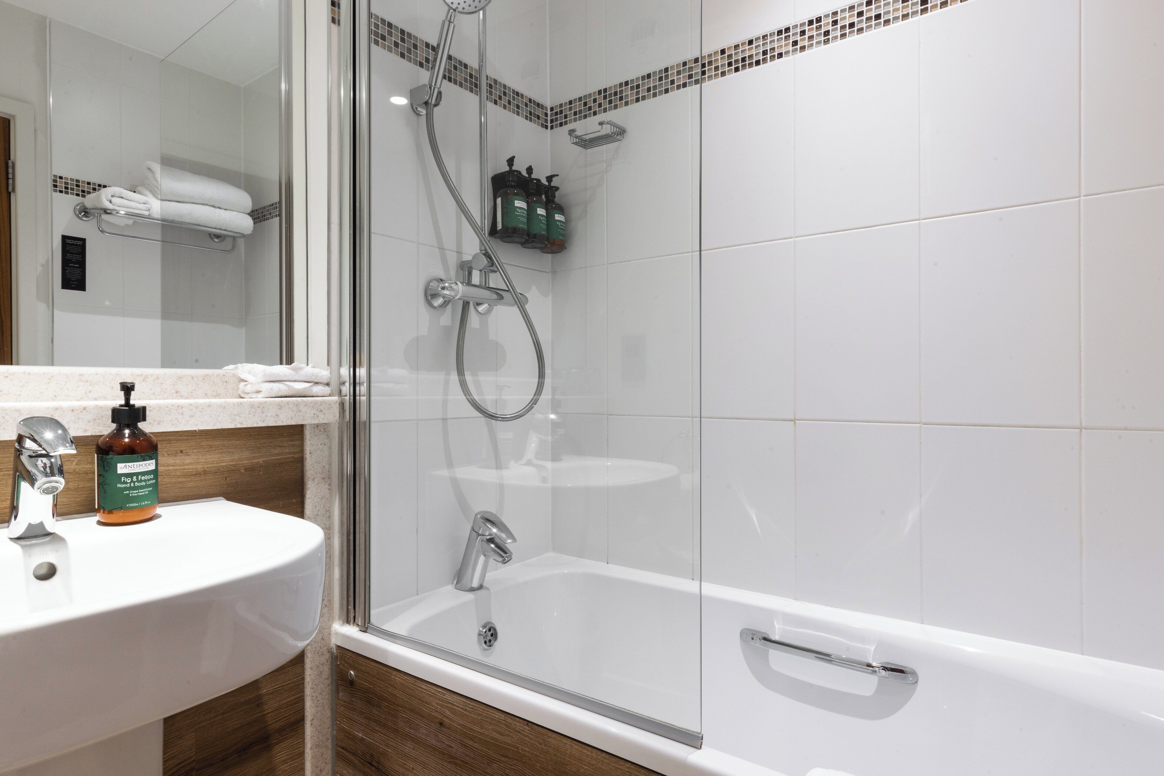 Un baño moderno con ducha acristalada, lavabo blanco y bañera.