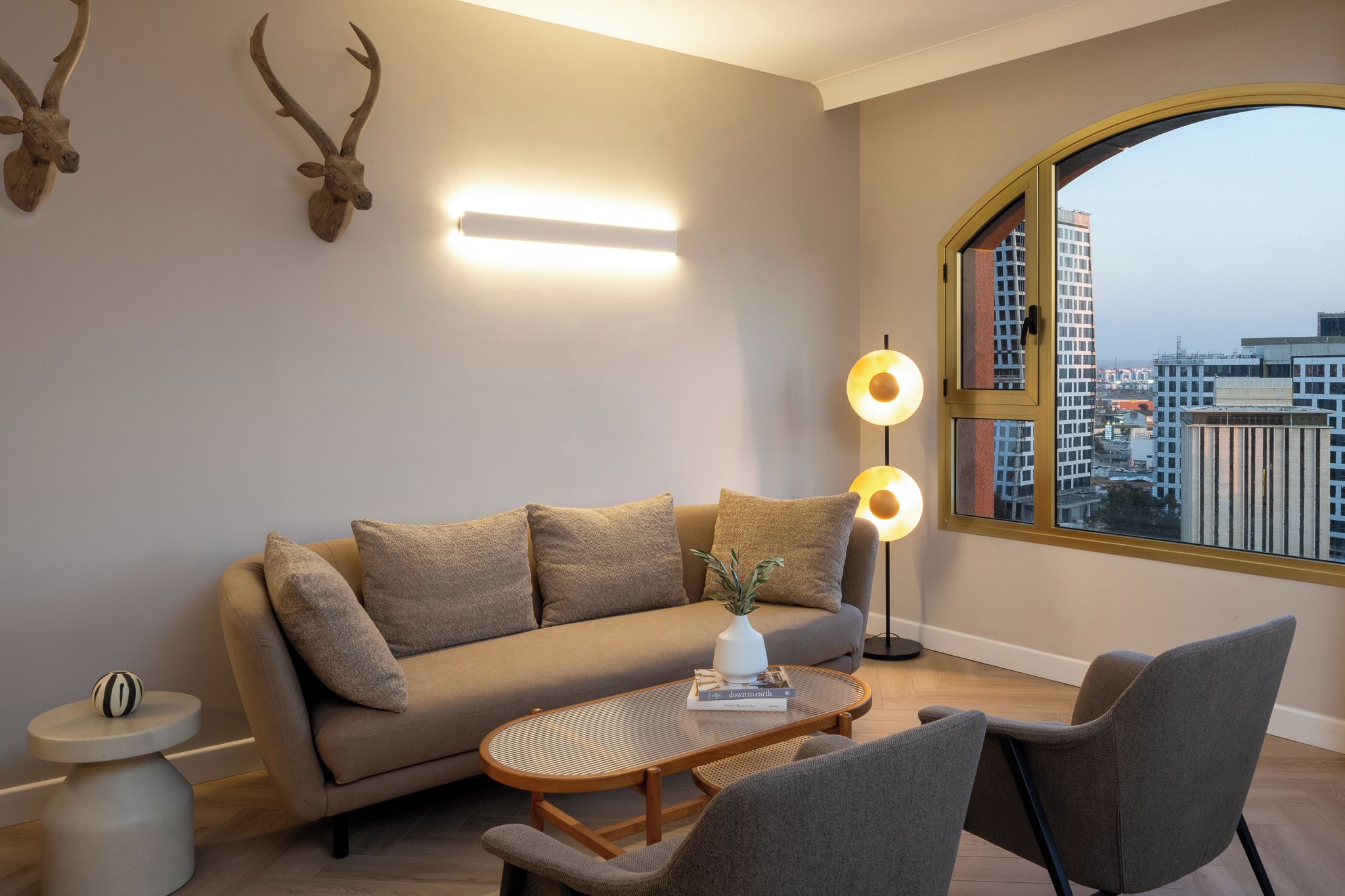 A modern living room with a sofa, armchairs, a coffee table, and a floor lamp.